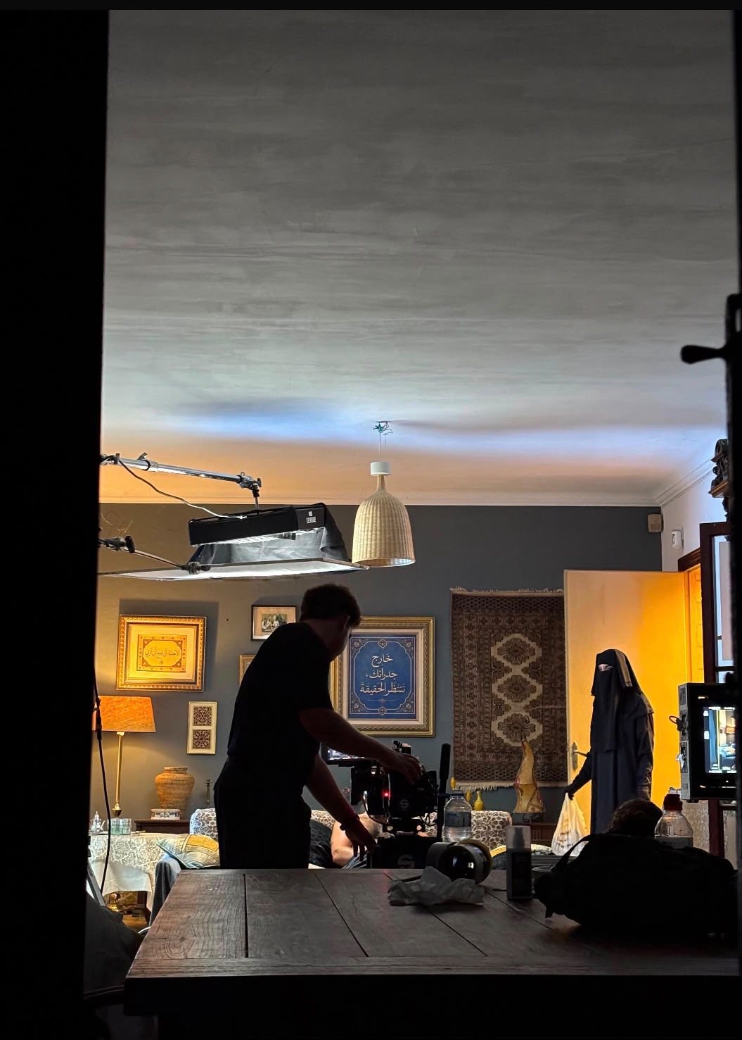 Crew filming in a living room seen through a doorway