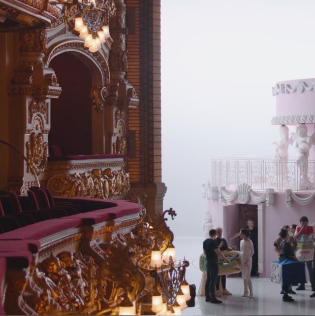 Gilded theatre box beside the giant pink cake set during rehearsal
